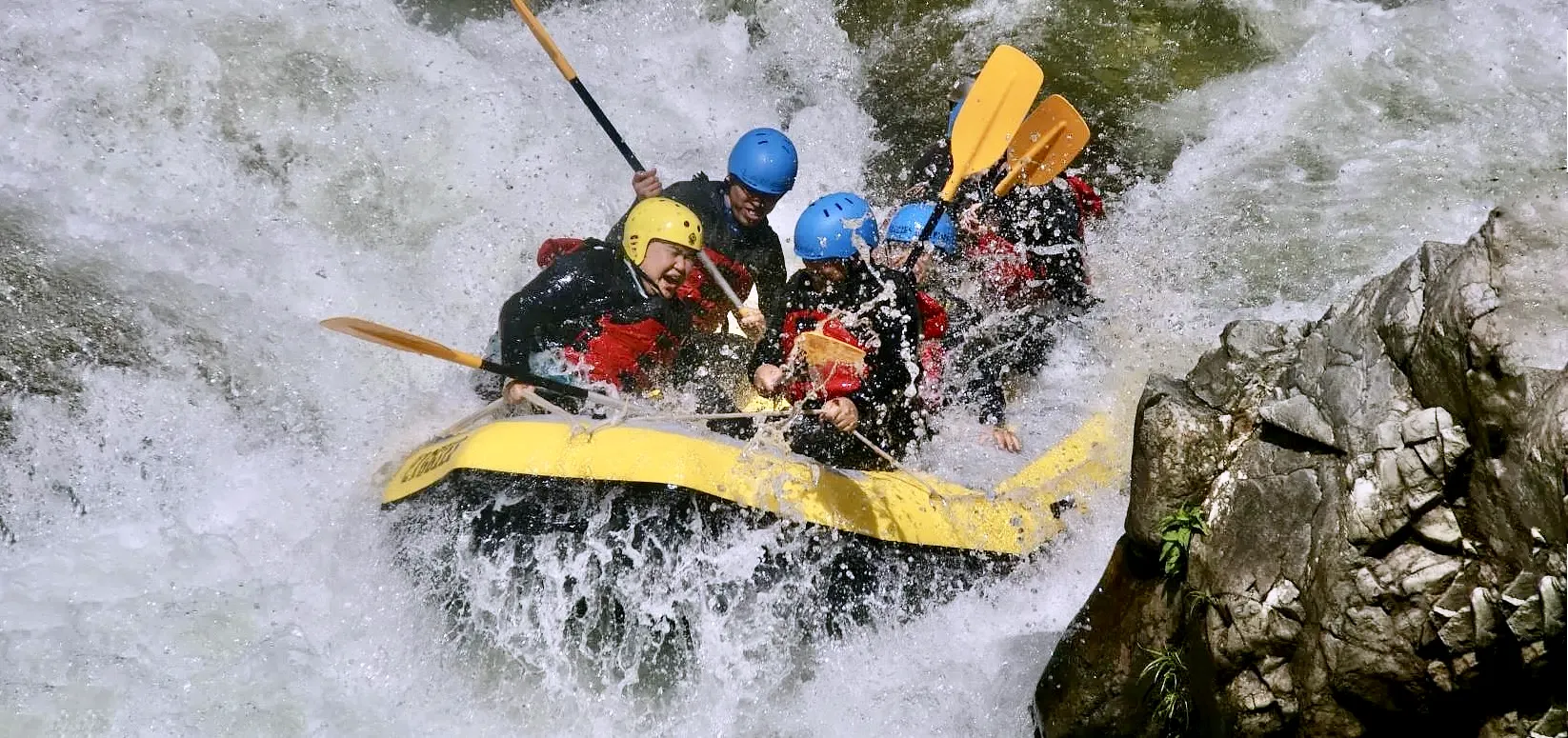 Thrilling Minakami rafting experience in Japan as a group tackles a steep rapid during a high-energy whitewater adventure tour, スリル満点のみなかみラフティング体験。グループが落差のある急流に突入する日本の白波アドベンチャーツアー。 
