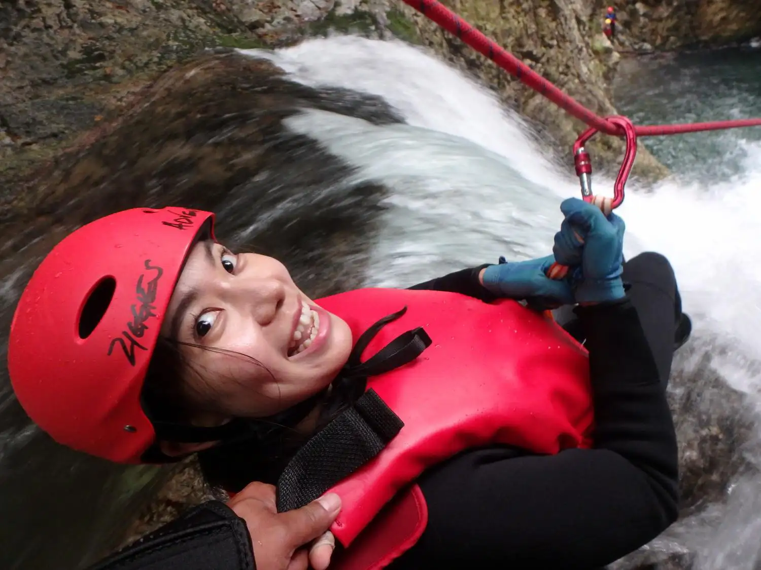 (水上)みなかみキャニオニング冒険者がエキサイティングなみなかみフォックスキャニオニング体験中に激しい滝の流れに浮かぶ様子. Minakami canyoning adventurer floating in rushing waterfall current during exciting minakami fox canyoning experience.